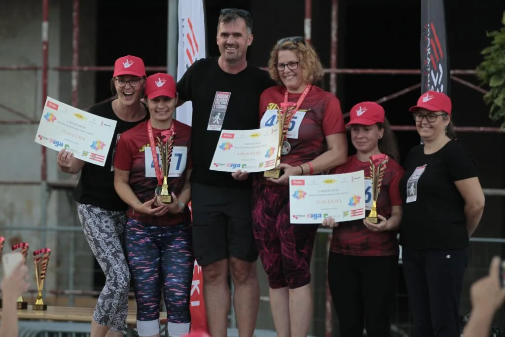 Participants and supporters celebrating with medals and awards after the 2025 race